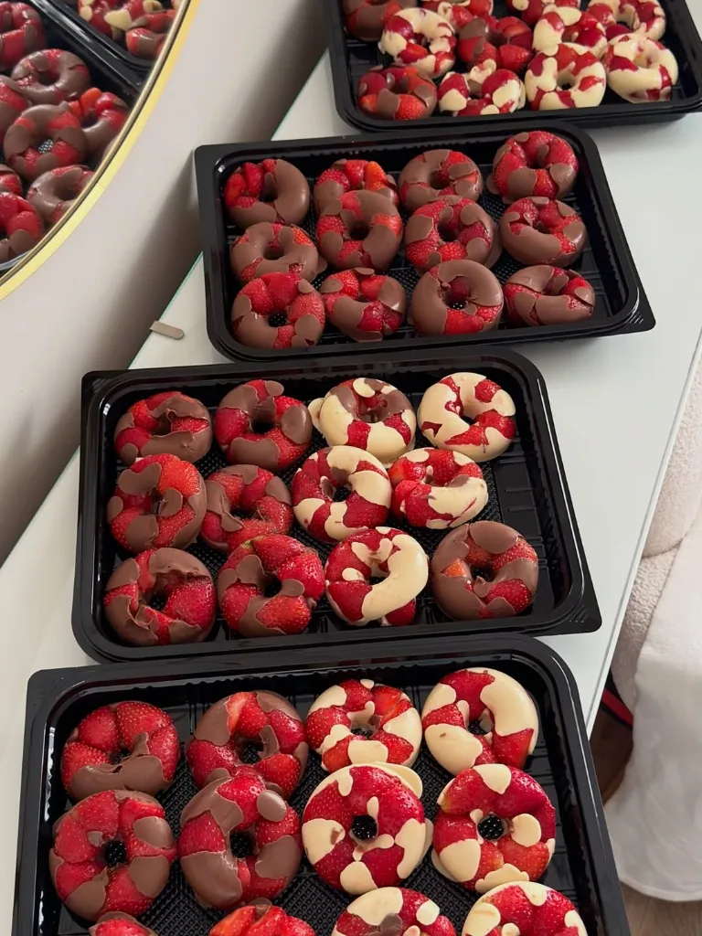 Bandejas de produção com dezenas de Fruit Donuts de morango e chocolate prontos na cozinha de casa