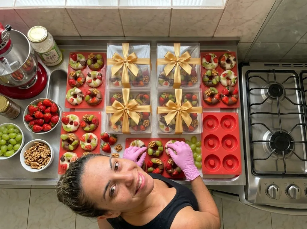 Aluna do Método Fruit Donuts em sua cozinha com caixas de presente e formas de silicone